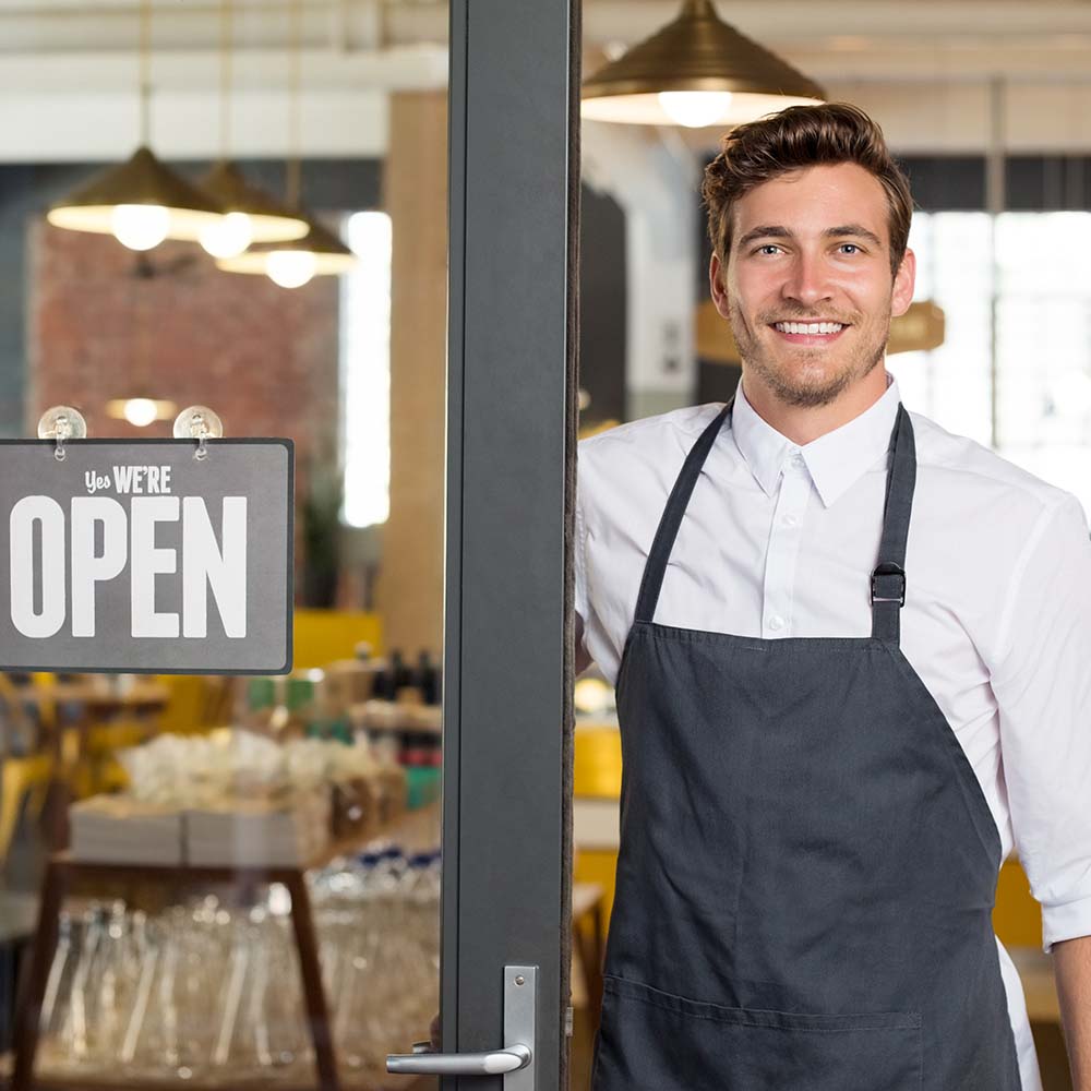man-in-apron-smiling-in-restaurant-doorway-westport-ma